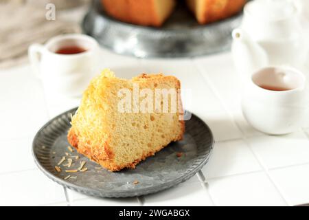 Gâteau en mousseline tranchée sur table blanche, servi avec du thé Banque D'Images