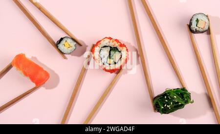 Divers Sushi japonais avec baguette sur table rose, vue de dessus Banque D'Images