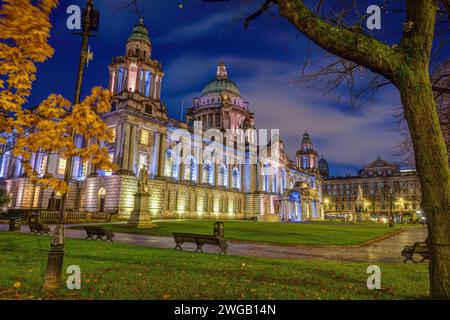 Le magnifique hôtel de ville de Belfast illuminé au crépuscule avec quelques arbres automnaux Banque D'Images