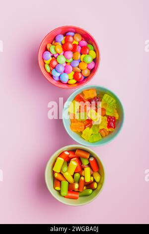 Bonbons de gelée sucrés colorés dans le bol sur le fond rose. Vue de dessus. Banque D'Images