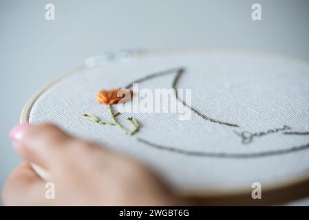 Main de femme tenant un cerceau de broderie avec un motif de lune fleurie Banque D'Images