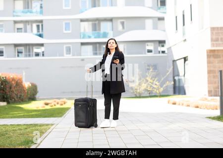 Femme debout devant un immeuble avec des bagages à roulettes, Allemagne Banque D'Images