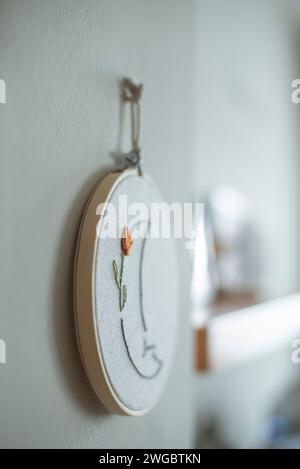 Cerceau de broderie avec un motif de lune fleuri accroché à un mur Banque D'Images