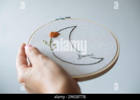 Main de femme tenant un cerceau de broderie avec un motif de lune fleurie Banque D'Images