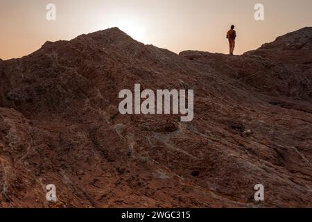 Baloutchistan - Pakistan - 16 janvier 2024 : silhouette d'un homme debout sur un rocher de la plage de Gadani au coucher du soleil. Banque D'Images