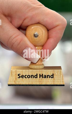 La main d'une femme tient un timbre en bois avec l'inscription : seconde main Banque D'Images