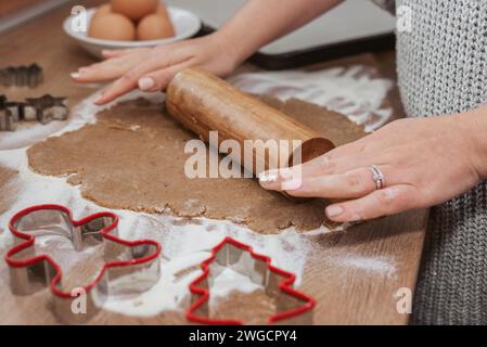 Photo en gros plan des mains à l'aide d'un rouleau à pâtisserie sur la pâte à biscuits pour biscuits au pain d'épices Banque D'Images
