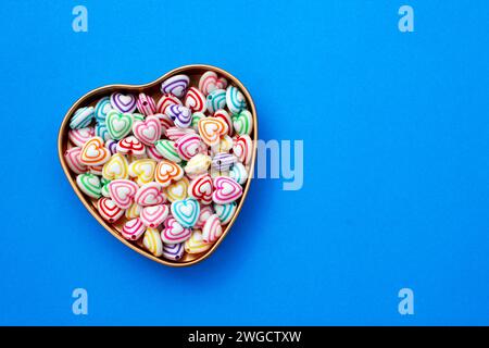 Récipient avec des perles avec des lignes colorées pour faire des colliers et des bracelets en forme de coeur Banque D'Images