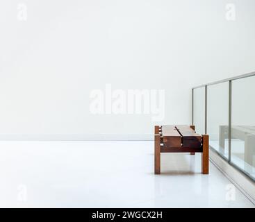 Banc en chêne rustique de coupe épaisse avec personne. Vide brun long siège de banc épais en bois sur un mur blanc près de la décoration de clôture de séparation en verre à l'intérieur du Banque D'Images