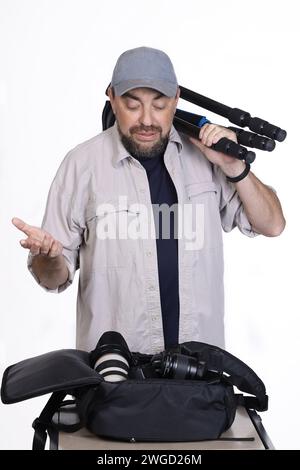 Photographe met l'équipement photo dans un sac à dos. Studio tourné sur fond blanc Banque D'Images