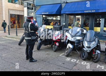 Un gardien de parking délivrant un avis de pénalité pour les motos garées à l'extérieur d'une zone désignée marquée dans la ville de Londres Angleterre Royaume-Uni Banque D'Images