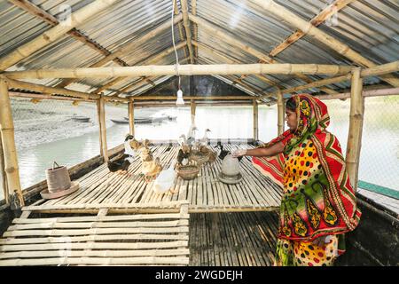 Une femme nourrit ses canards dans une ferme de poulaillers d'eau solaire. L'architecte Rezwan a conçu l'élevage solaire de l'eau qui comprend une enceinte circulaire portable créée par des filets de pêche et des bandes de bambou (pour élever le poisson) et un canard flottant alimenté par une lampe solaire. Il a un système de recyclage - le fumier de canard est utilisé comme nourriture pour poissons, les vieux lits de jacinthe d'eau sont vendus comme engrais organique, et l'énergie solaire allume le canard pour maintenir la production d'œufs. En outre, on assiste à une sensibilisation accrue aux adaptations au changement climatique dans les communautés sujettes aux inondations. Hariabari, B. L. bari, Faridpur, Pabna. Bangladesh. Banque D'Images