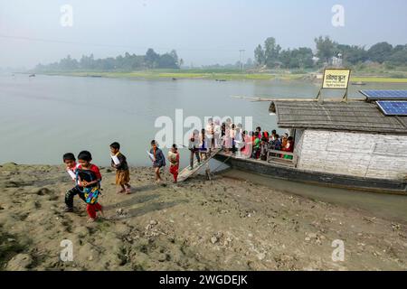 Les élèves du village suivent un cours à l'école de bateau de Chalk Lanka. Le pays a été inondé à deux reprises en 2007 et 332 écoles ont été détruites et 4 893 écoles ont été endommagées. Shidhulai exploite une flotte d'écoles flottantes, de bibliothèques, de cliniques de santé, d'ateliers solaires et de centres de formation flottants avec accès Internet sans fil, desservant près de 97 000 familles dans les régions sujettes aux inondations. Les bateaux eux-mêmes sont équipés de panneaux solaires qui alimentent les ordinateurs, les lumières et le matériel médical. Singra, Natore, Bangladesh. Banque D'Images