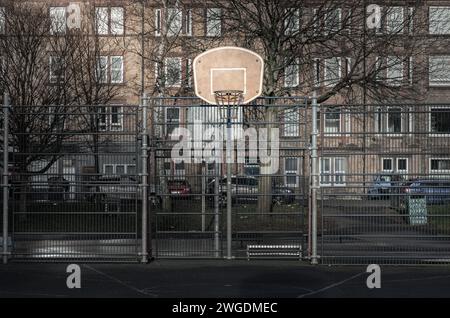 Édimbourg, Écosse, 19 janvier 2024 - panneau de basket-ball avec l'anneau métallique cerceau sur les terrains de basket-ball extérieurs dans le parc avec de vieux bâtiments backgrou Banque D'Images