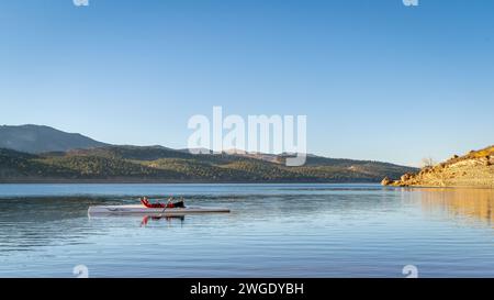 Rameur mâle repose dans sa coquille d'aviron sur carter Lake dans les paysages d'automne ou d'hiver dans le nord du Colorado Banque D'Images