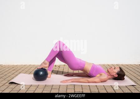 fit femme sportive faisant des exercices de pilates ball à l'extérieur. Posture du pont Banque D'Images