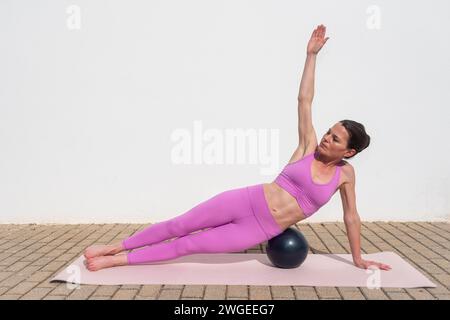 fit femme sportive faisant des exercices de pilates ball à l'extérieur. Planche latérale Banque D'Images