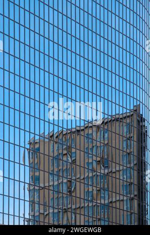 Gratte-ciel en verre bleu avec le reflet d'un autre bâtiment dans la ville Banque D'Images