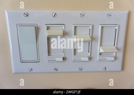 Ensemble de variateurs d'interrupteur de lumière avec différents réglages sur une plaque en plastique sur un mur beige Banque D'Images