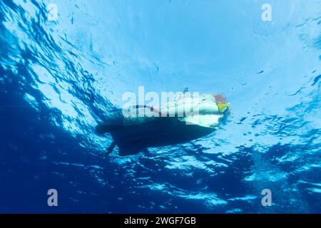 Vue depuis le bas du petit bateau de plongée flottant au-dessus dans les eaux tropicales bleues claires Banque D'Images