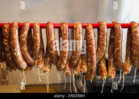 Nourriture traditionnelle. Saucisses crues suspendues et préparées pour être fumées dans un fumoir domestique. Banque D'Images