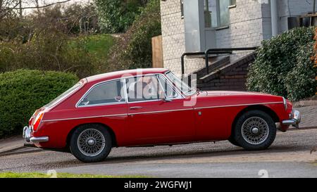 Milton Keynes, UK-4 février 2024 : 1970 rouge MGB GT voiture classique conduisant sur une route anglaise. Banque D'Images
