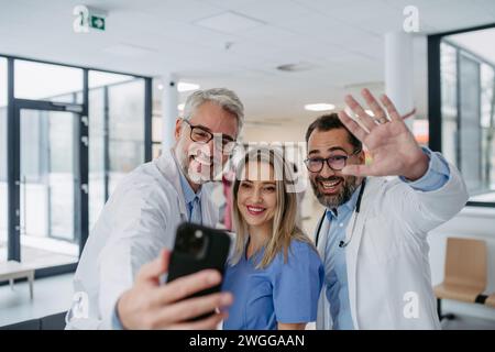 Portrait de médecins et d'infirmières debout dans le couloir hospitalier. Travailleurs de la santé dans une clinique privée moderne, prenant selfie, souriant. Banque D'Images