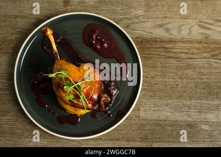 Cuisse de canard rôtie sur purée de pommes de terre avec oignon, crème de chou violet et jus de myrtille Banque D'Images