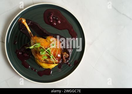 Cuisse de canard rôtie sur purée de pommes de terre avec oignon, crème de chou violet et jus de myrtille Banque D'Images