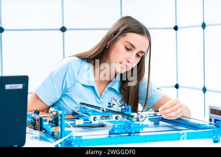 jeune femme étudiant la robotique dans un laboratoire de programmation industrielle Banque D'Images