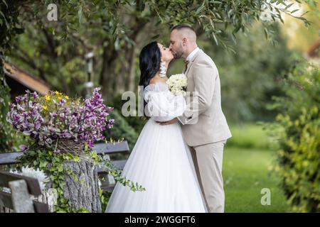 Les jeunes mariés s'embrassent après la cérémonie de mariage. Banque D'Images
