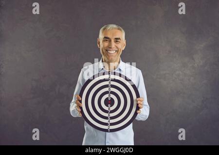 Portrait de l'homme heureux tenir le tableau de fléchettes avec la cible Banque D'Images