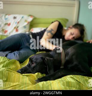 Jeune femme et son chien se détendent ensemble tout en étant couché sur le lit (grand danois). Banque D'Images