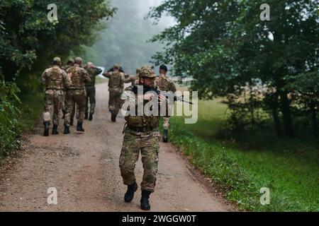 Un groupe de soldats d'élite conduit les captifs dans un camp militaire, mettant en évidence une atmosphère tendue de détention et d'opérations de sécurité Banque D'Images