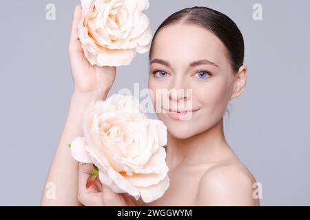 Beau modèle avec fleur. Maquillage de visage de femme parfait en gros plan. Rouge à lèvres. Beaux ongles. Beau sourire. Peau parfaite Banque D'Images