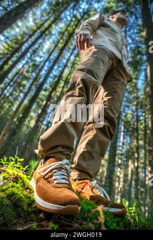 Jeune randonneur masculin regardant loin tout en se tenant debout contre des arbres dans la forêt Banque D'Images