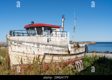Un vieux bateau repose sur des rives sablonneuses, révélant son pont et son moteur Banque D'Images
