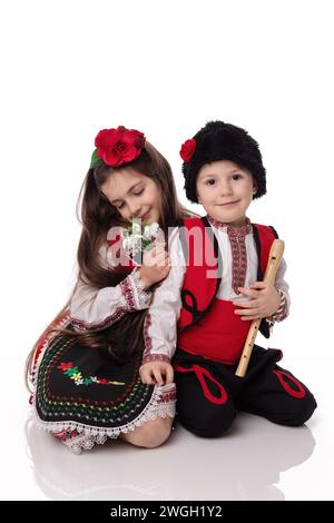 Garçons et filles bulgares en costumes traditionnels folkloriques avec fleurs printanières en forme de goutte d'eau et bracelet en laine martenitsa, symbole de Baba Marta Banque D'Images