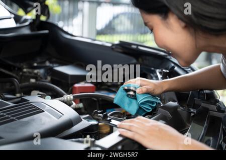 Une femme vérifie le niveau de liquide de refroidissement du moteur. Banque D'Images