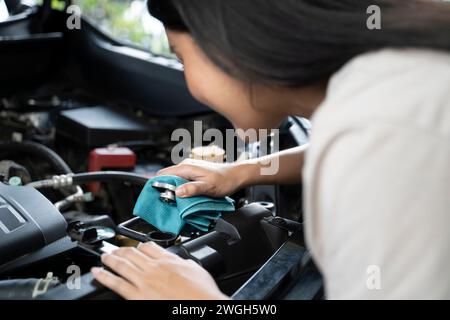 Une femme vérifie le niveau de liquide de refroidissement du moteur. Banque D'Images