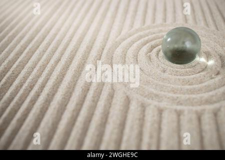 Jardin zen en sable miniature avec sphère de verre et dunes géométriques, texture abstraite Banque D'Images