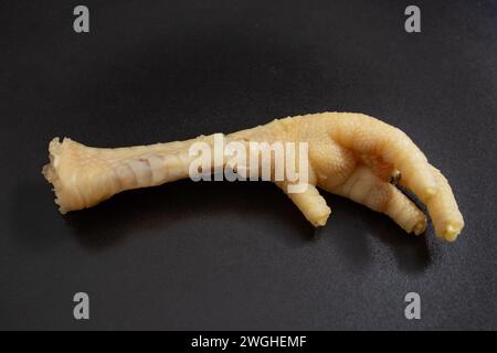 Pied de poulet bouilli sur une texture de plaque de céramique noire, fond de crise alimentaire Banque D'Images