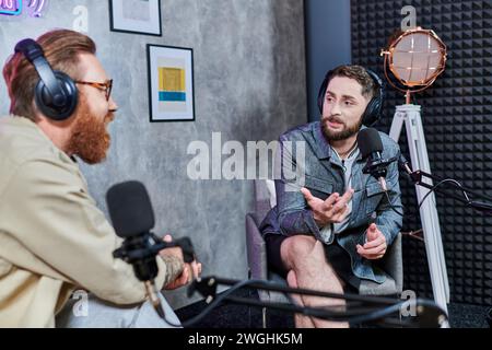 intervieweur attrayant avec les cheveux roux et son invité avec des écouteurs discutant des questions, podcast Banque D'Images