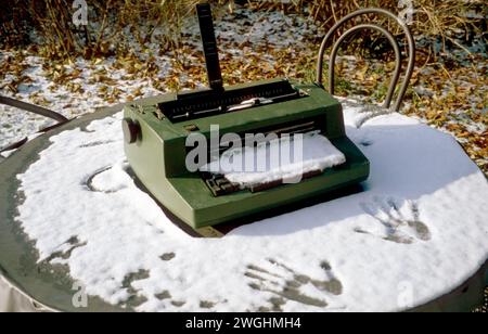 Une machine à écrire à tête sphérique corrective IBM Selectric II, modèle XYD, mise hors service, en hiver sur une table de jardin, deux empreintes d'une main à côté Banque D'Images
