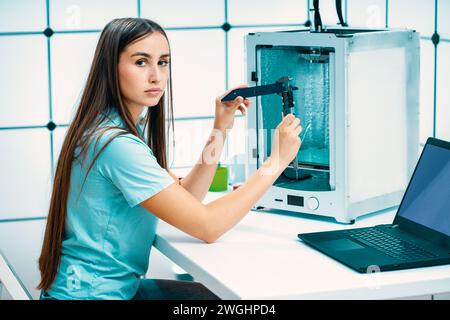 Jeune femme utilise une imprimante 3D pour réaliser des prototypes de dispositifs industriels Banque D'Images