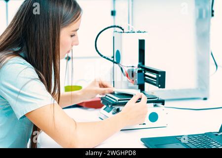 Jeune femme utilise une imprimante 3D pour réaliser des prototypes de dispositifs industriels Banque D'Images