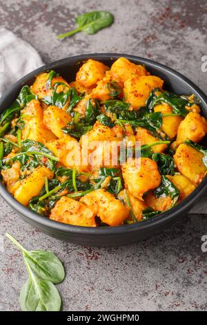 Plat de curry épicé à base de pommes de terre et d'épinards saag aloo gros plan sur l'assiette sur la table. Vertical Banque D'Images