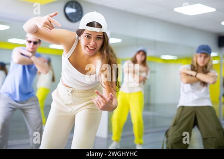 Garçons et filles dansant la chorégraphie de groupe synchrone dans la salle de danse Banque D'Images