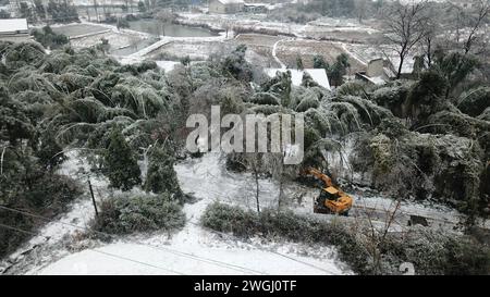 Changsha. 5 février 2024. Une photo prise par un drone aérien le 5 février 2024 montre un membre du personnel enlevant de la glace et des branches tombées d'une route dans le canton de Tandu à Linxiang, dans la province du Hunan au centre de la Chine. Dimanche, le ministère de la gestion des urgences a amélioré l'intervention d'urgence pour les catastrophes provoquées par les basses températures, la pluie, la neige et le gel dans la province du Hunan, au centre de la Chine, du niveau IV au niveau III. Crédit : Chen Zhenhai/Xinhua/Alamy Live News Banque D'Images