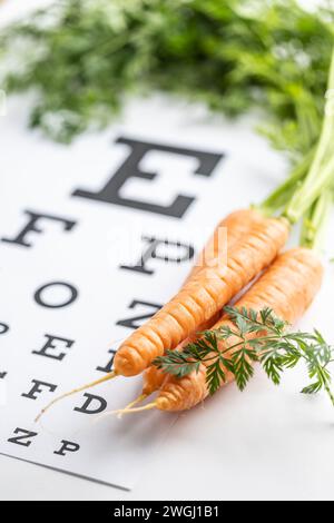 Carottes fraîches comme source de vitamine A placée sur le tableau de test oculaire. Banque D'Images